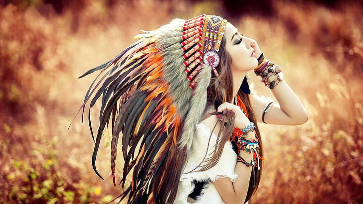 women's white top, photo of a woman closing her eyes wearing black and brown Native American headdress