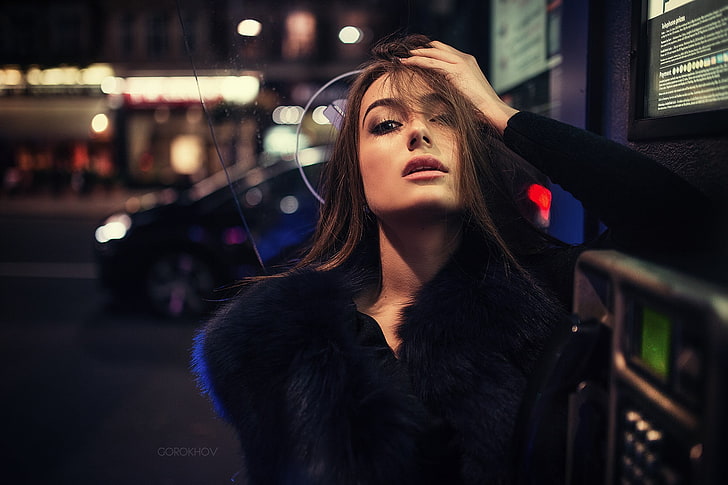 selective focus photography of woman wearing black fur coat during nighttime