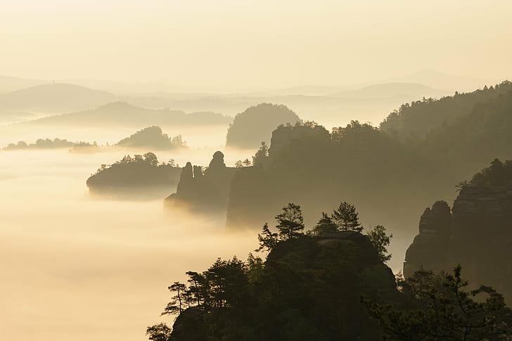 silhouette of rock formations surrounded by fog during daytime