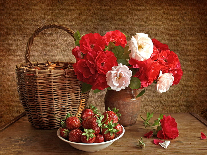bowl of strawberries, brown wicker basket, and pot of flowers