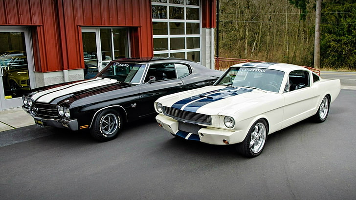 two black and white coupes beside red building at daytime, car