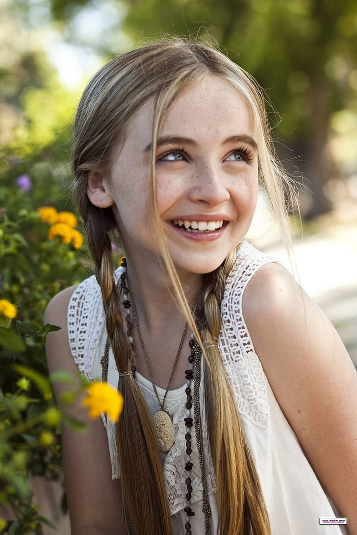 girl's white floral lace sleeveless top, Sabrina Carpenter, smiling