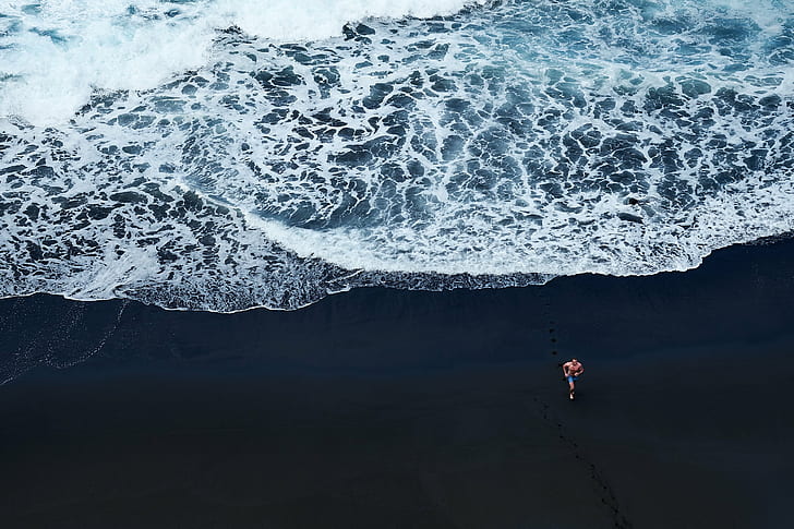 person walking on black sand near body of water, beach, men, white  water