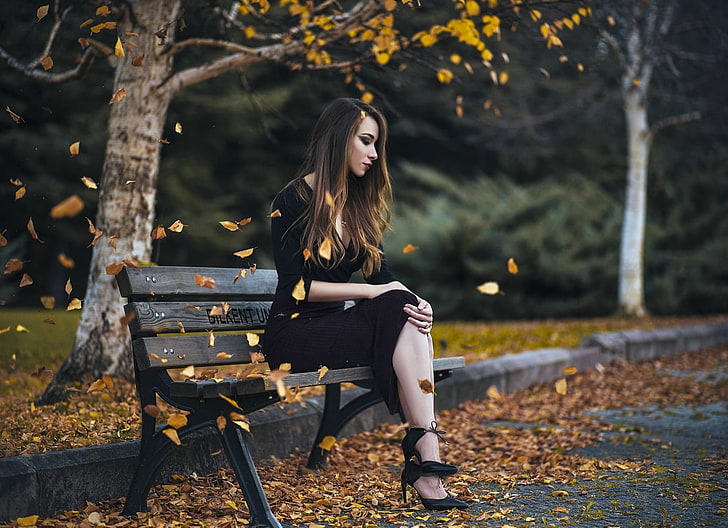 woman sitting on bench beside road, woman in black dress sitting