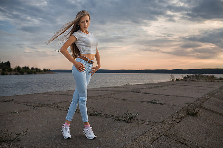 women's white short-sleeved crop top, women outdoors, jeans, legs crossed