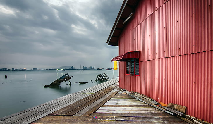 red painted galvanized iron walled building next to body of water