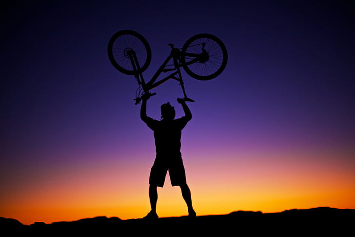 silhouette of man carrying mountain bike during sunset, BIker