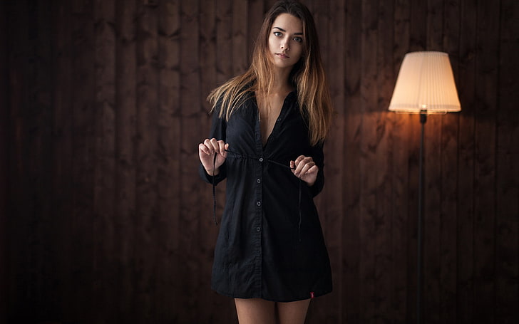 woman wearing black button-up dress near white and black floor lamp inside room