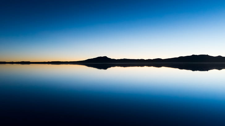 panoramic photo of island's silhouette near body of water at sunrise