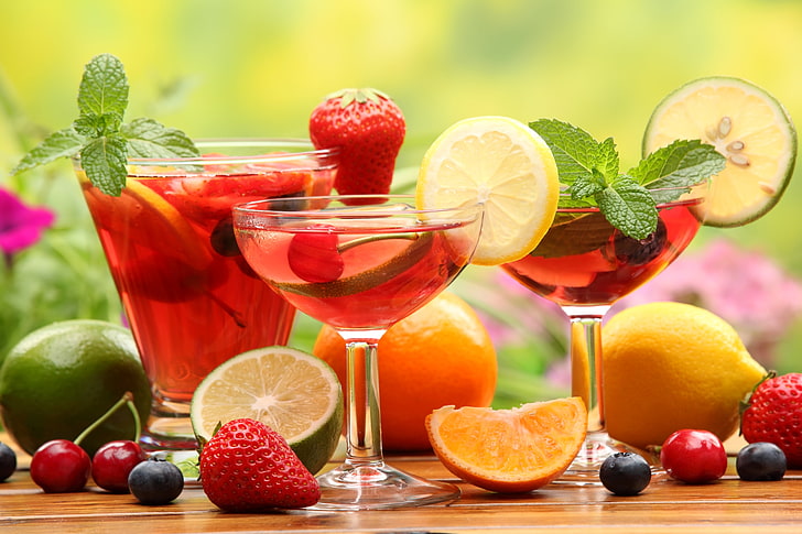 selective focus photography of strawberry, lemon, cherries, oranges, and lemons beside glass of juice